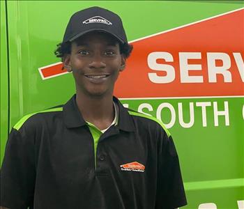 SERVPRO of South Charlotte employee, in uniform, standing in front of a green work van.